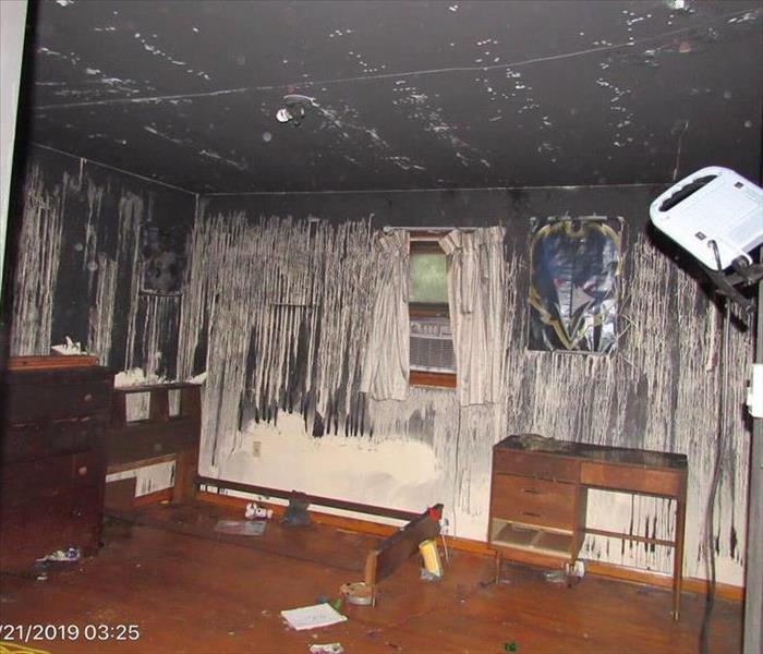A bedroom with soot running down the walls.