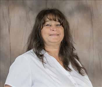 A female with brown hair wearing a white shirt. 