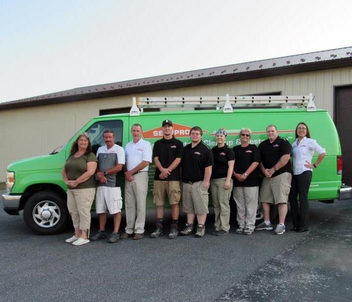 A group photos of all staff in front of a fleet van.