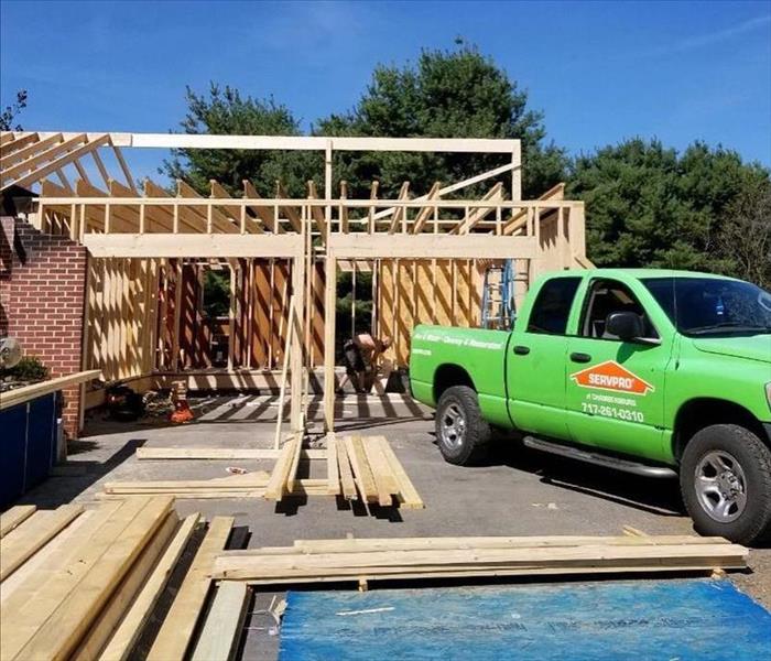 A garage with new wood framing with a green SERVPRO truck