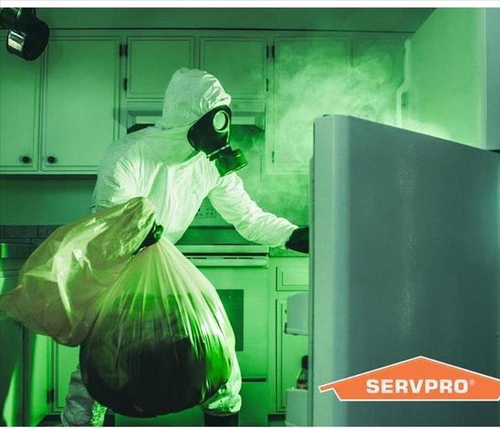 A person in a protective white cleaning out a refrigerator 