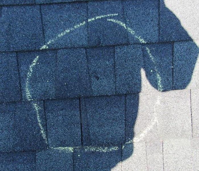 A roof shingle with a chalk mark to indentify damage